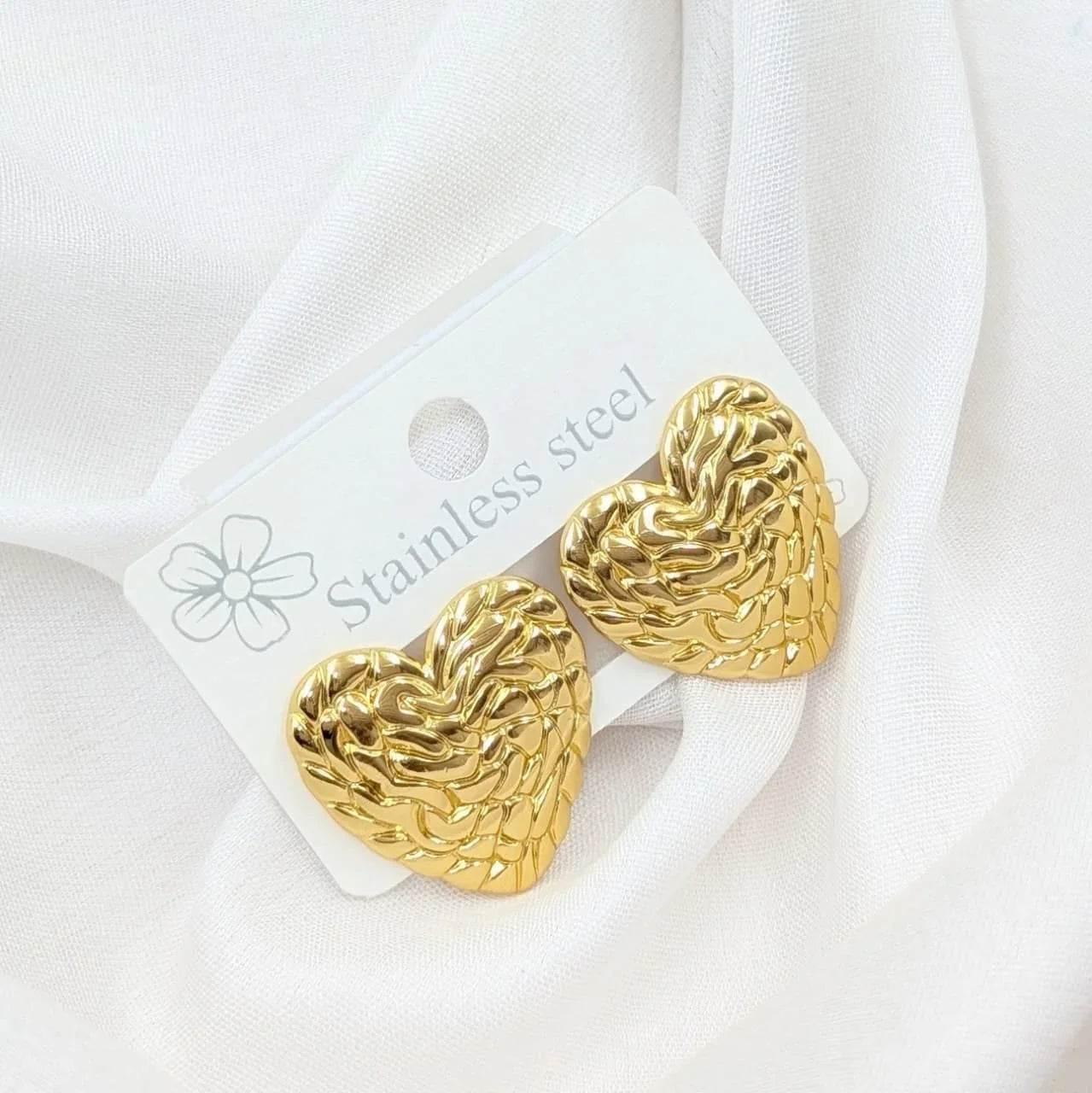 Gold heart-shaped earrings on a white card with 'Stainless steel' text, against a white background.