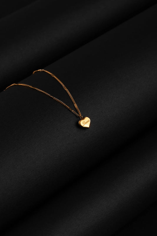 Gold heart-shaped pendant necklace on a black background