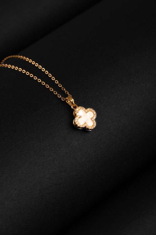 Gold necklace with a clover-shaped pendant on a black background
