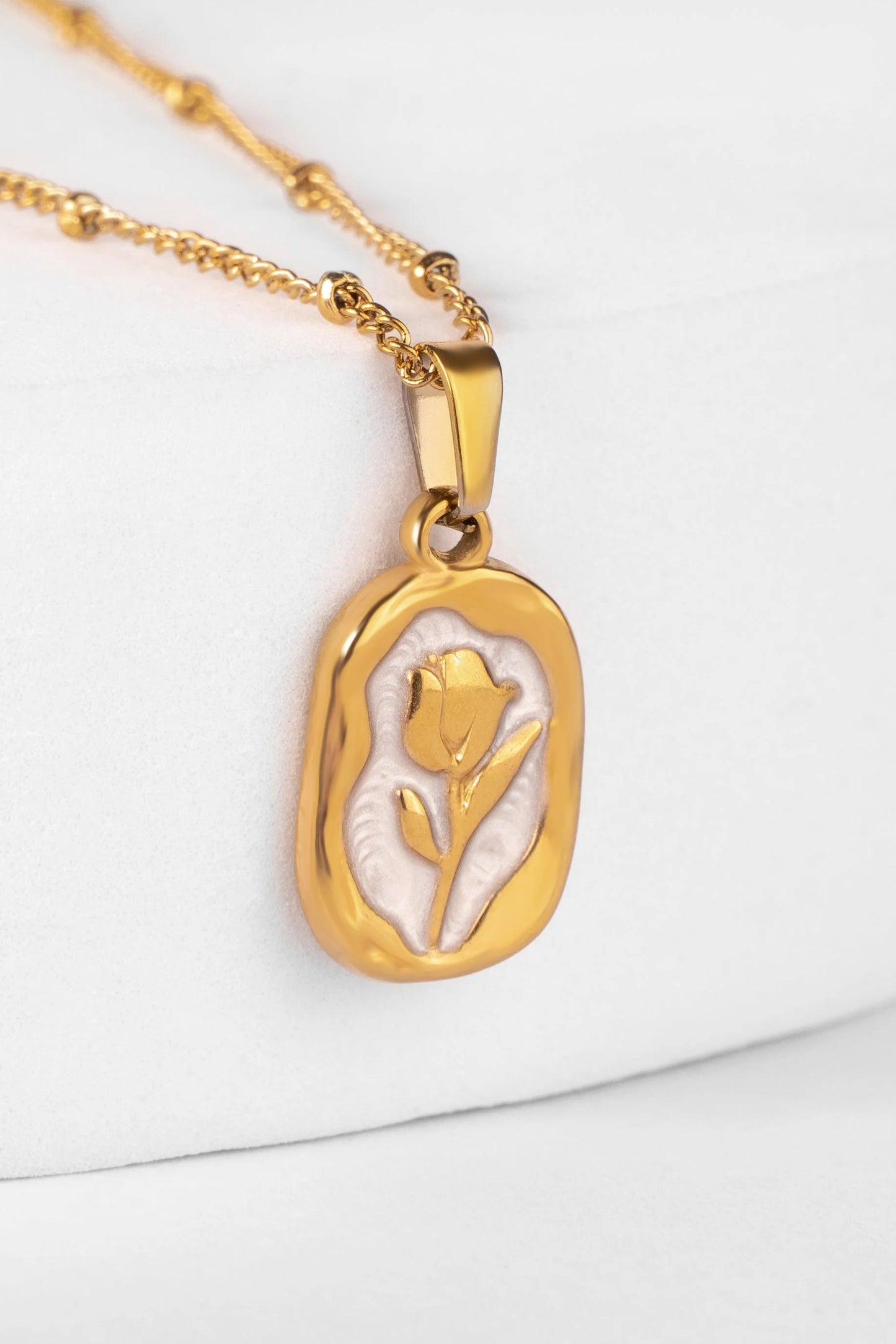 Gold necklace with a pendant featuring a tulip design on a white background