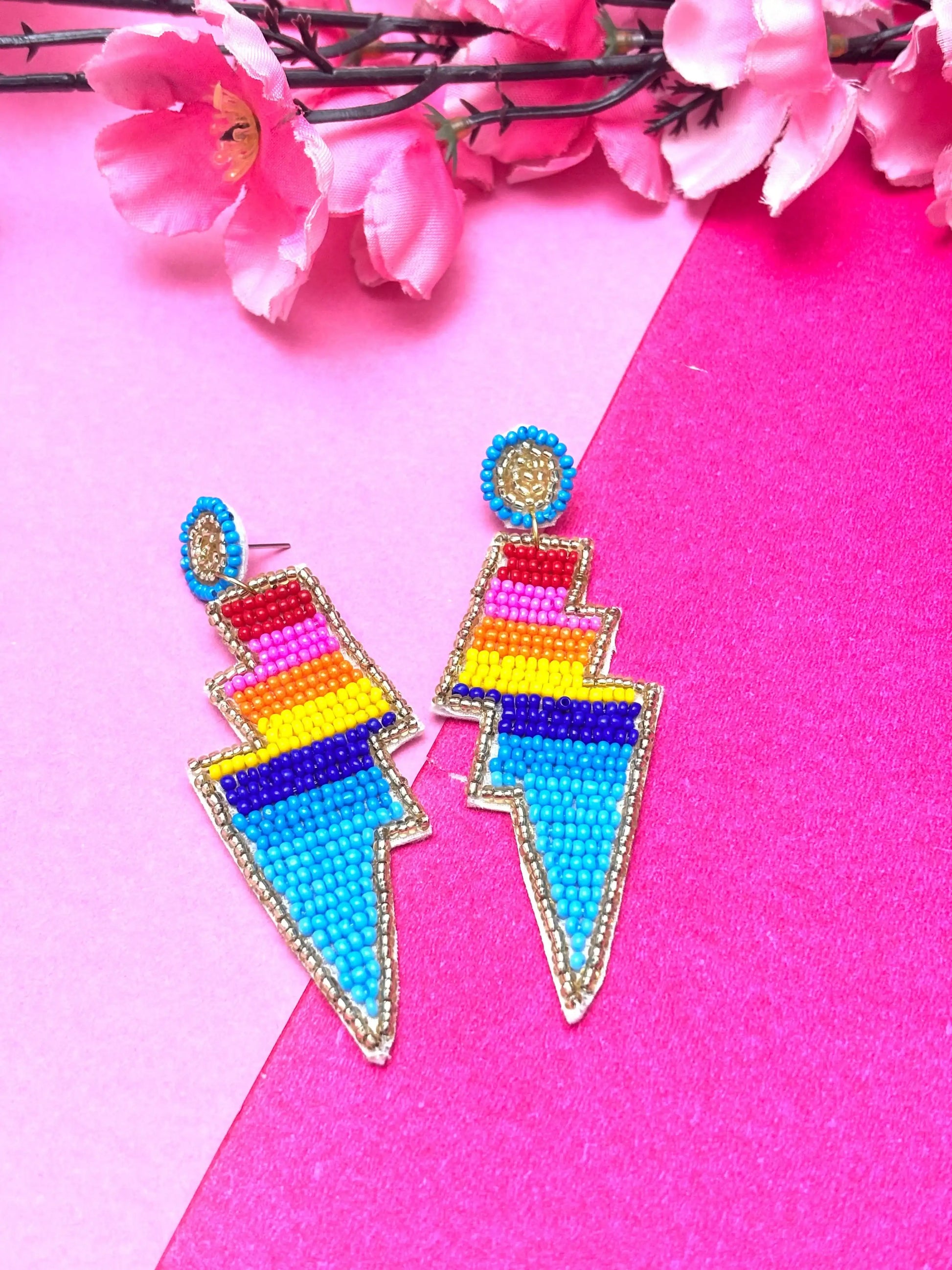 Colorful beaded earrings on a pink background with flowers