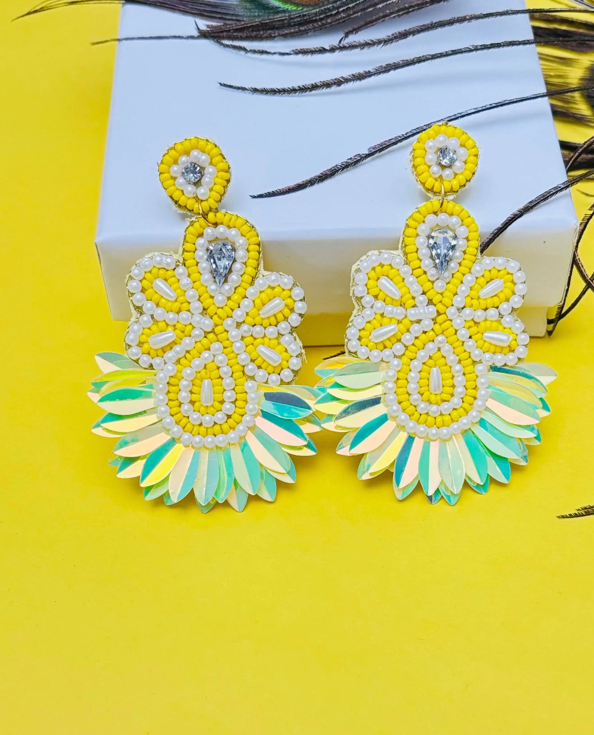 Pair of yellow and green earrings on a yellow background