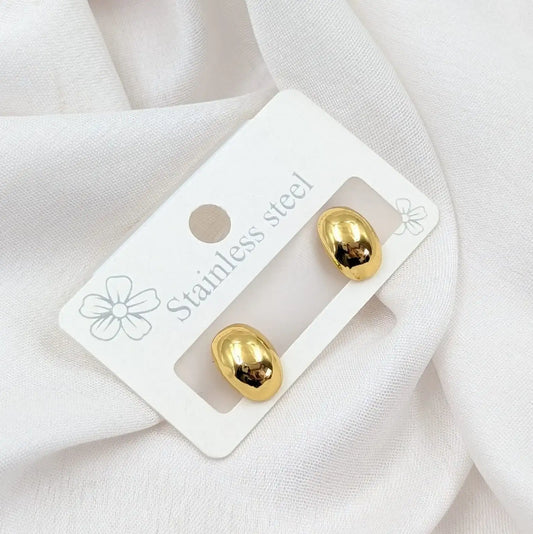 Gold earrings on a white card with 'Stainless steel' text, placed on a white fabric background.